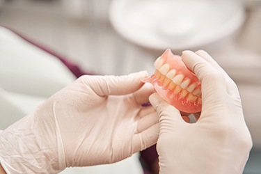 Gloved hands holding full set of dentures