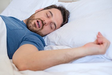 Man snoring fitfully in bed