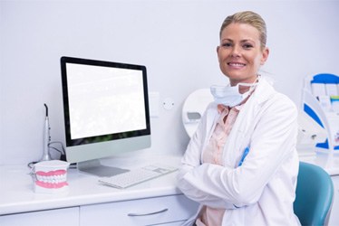 Dental team member smiling while sitting at computer