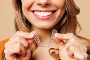 Close-up of woman holding Invisalign aligner close to her mouth