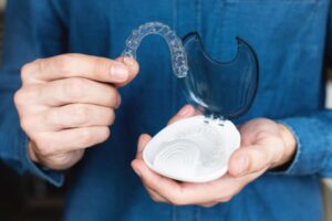 Man taking Invisalign aligner out of its storage case