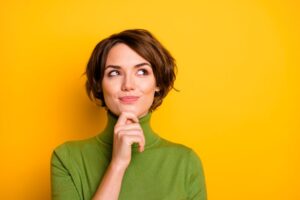 Woman in green turtleneck, wearing curious expression