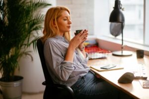 Woman sitting at desk, enjoying a cup of coffee