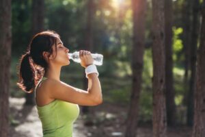 Woman standing outdoors, drinking from water bottle